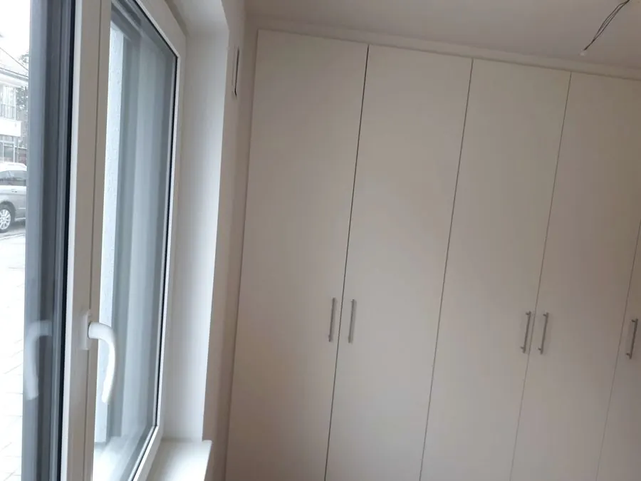Raumhohe weiße Einbauschrankwand mit Stangengriffen neben dem Fenster — Björn Schillinger Schreinermeister, Germering