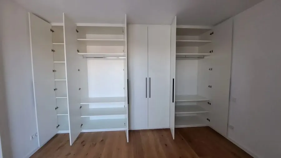 Geöffneter weißer Einbauschrank mit Fachböden und Kleiderstangen — Björn Schillinger Schreinermeister, Germering