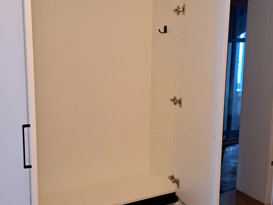 Geöffneter weißer Garderobenschrank mit Hakenstange und Auszug darunter — Björn Schillinger Schreinermeister, Germering
